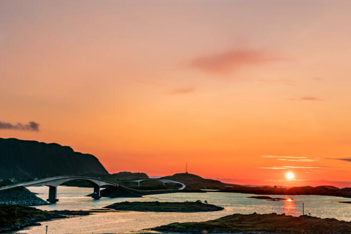 Midnight sun in Lofoten with the Norwegian sea and scenic road with bridges in the background