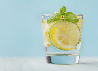 7 razlogov zakaj moraš začeti piti limonino vodo! Mineral infused water with limes, lemons, ice and mint leaves on blue background, homemade detox soda water recipe