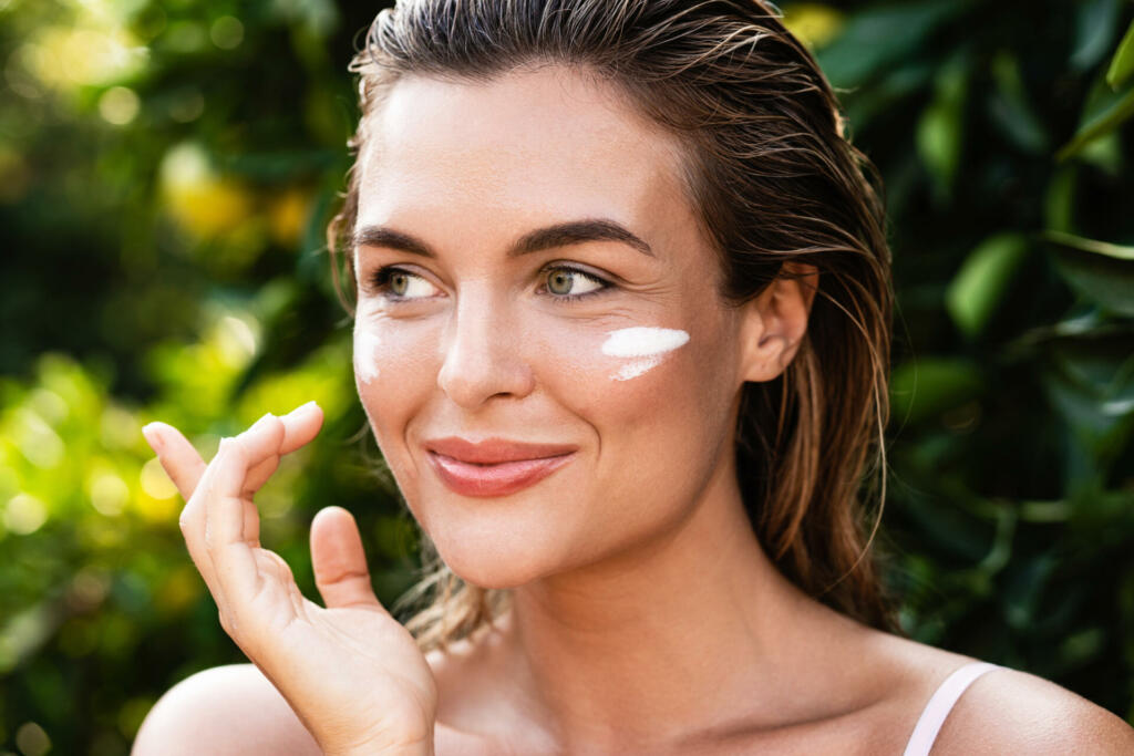 Outdoor portrait of beautiful woman with moisturizing cream under her eyes