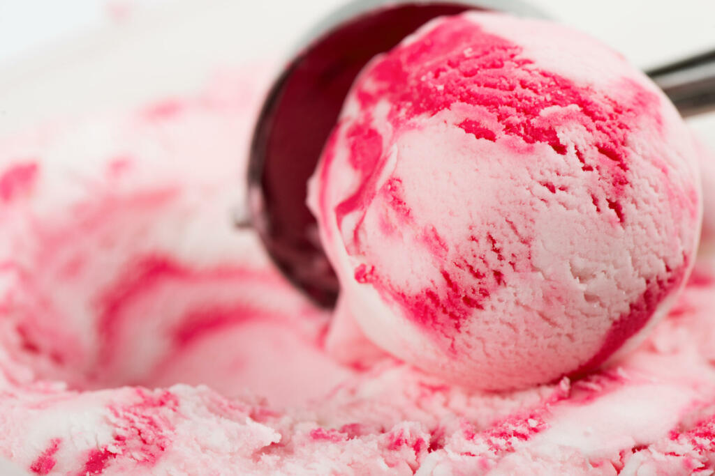 Ripple (vanilla raspberry or strawberry) ice cream scooped out of a container with a utensil.
