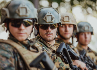 Kako mlade spodbuditi k služenju vojaškega roka? Soldier fighters standing together with guns. Group portrait of US army elite members, private military company servicemen, anti terrorist squad.