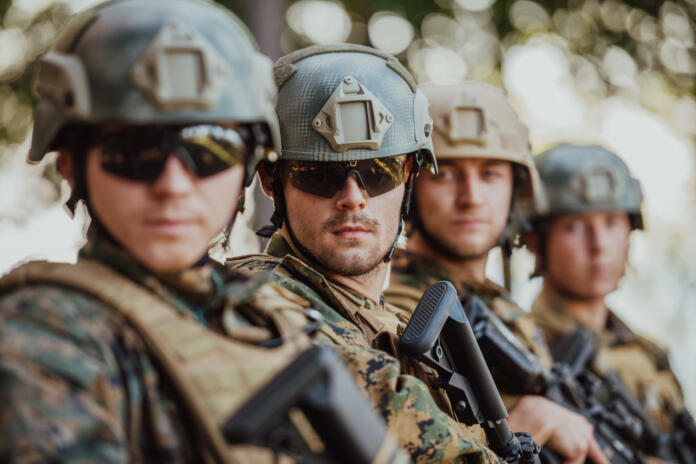 Soldier fighters standing together with guns. Group portrait of US army elite members, private military company servicemen, anti terrorist squad.