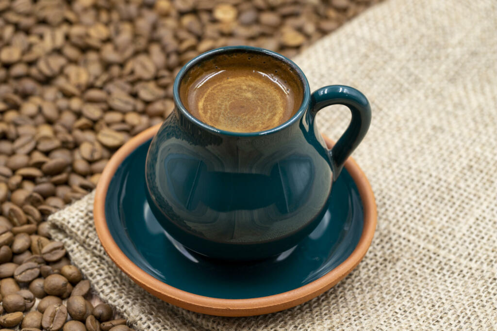 Turkish coffee on wood floor. Rustic turkish coffee cup on cloth. coffee beans in the background