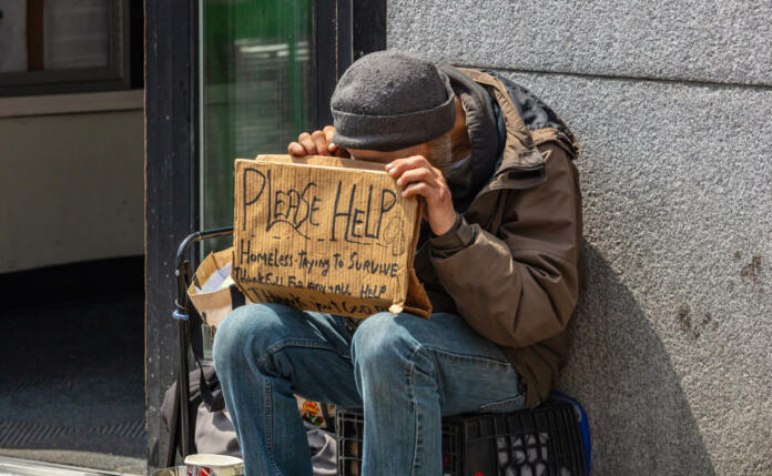 USA, New York. May 2, 2019. Homeless man holding a cardboard sign, asking for help, Manhattan downtown, sunny day in spring