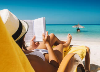7 neleposlovnih knjig, ki jih za poletje 2023 priporoča The New York Times Woman on sunbed reading book under parasol at tropical island
