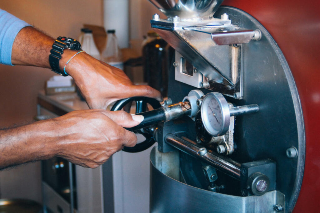 Roki držita ročko s kavo v avtomatu za praženje kave