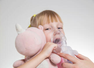 Nov žarek upanja za bolnike s cistično fibrozo A 5-year-old girl breathes into an inhaler to dilute sputum in case of lung diseases. Treatment of cough in children