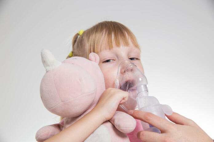 A 5-year-old girl breathes into an inhaler to dilute sputum in case of lung diseases. Treatment of cough in children