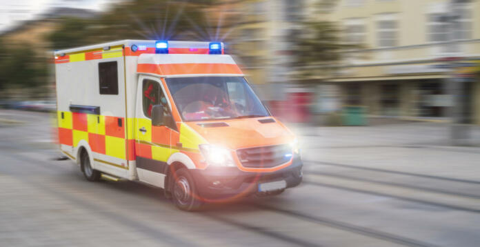 An emergency vehicle drives through the city with blue lights and high speed