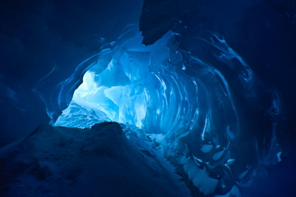 blue ice cave covered with snow and flooded with light