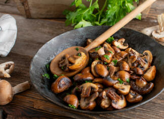 Sanje vseh slabih kuharjev, zakaj je nemogoče razkuhati to živilo? Delicious side dish or snack with pan fried mushrooms, champignons cooked with butter, herbs, pepper and salt. Served in a rustic cast iron pan on wooden table.