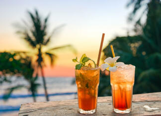 Najboljši brezalkoholni koktajli za poletje 2024 drinks with blur beach and sunset in background