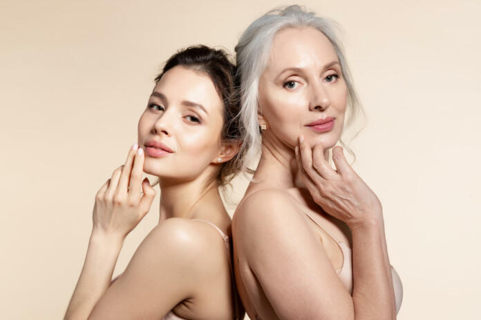 Elderly and young women with smooth skin and natural makeup standing back-to-back. Thinking, planning, dreaming