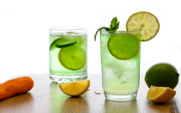 Gin tonic cocktails garnish with fresh mint and lime slice on bar counter in restaurant against on white background.