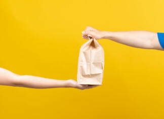 Študenti, ali koristite to ugodnost med poletjem? Hand to hand of Delivery food service sending delicious from restaurant to customer without having to leave the house receiver shipping deliver shopping online on yellow background isolated.