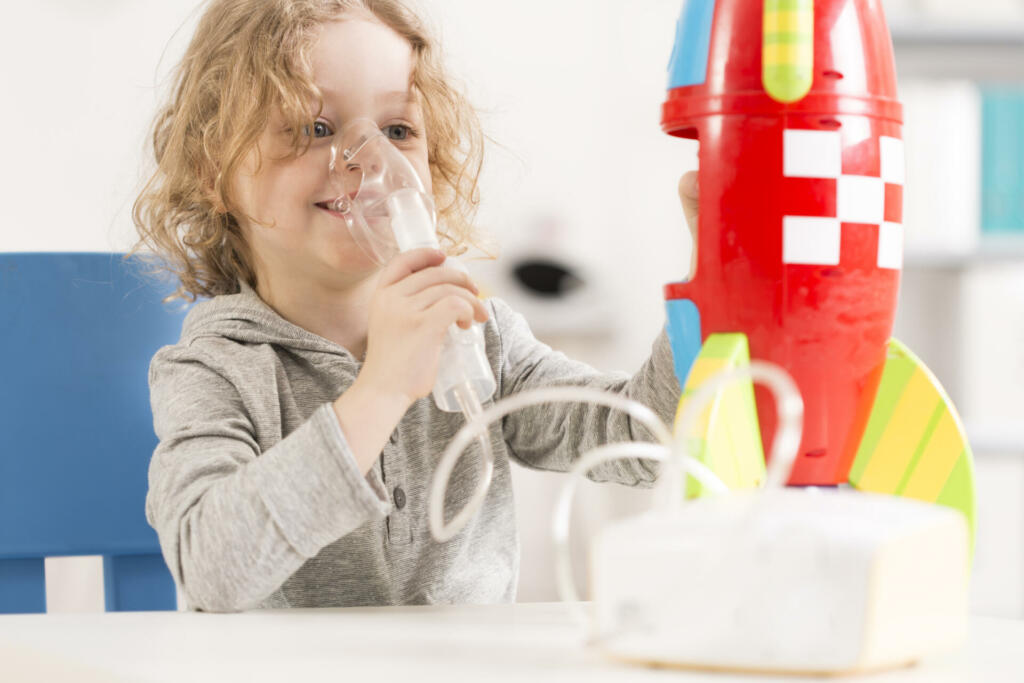 Happy child with oxygen mask playing with toy racket