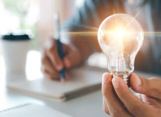 Če ti med epidemijo ni bilo dolgčas, si kreativna oseba, pravi nova študija Innovation through ideas and inspiration ideas. Human hand holding light bulb to illuminate, idea of creativity and inspiration concept of sustainable business development.