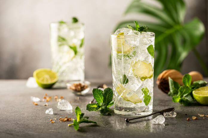 Mojito cocktail with lime and mint in highball glass on a grey background. Summer cold beverages concept with copy space