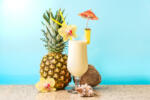 Pina Colada Cocktail Drink with pineapple and coconut, blue background, copy space. Summer tropical delicious cocktail with fruits and flowers, vacation concept.