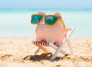 S temi nasveti boš na počitnicah privarčeval goro denarja Pink Piggy Bank Wearing Wooden Sunglasses Kept On The Deck Chair At Beach