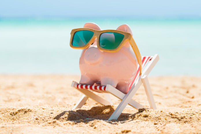 Pink Piggy Bank Wearing Wooden Sunglasses Kept On The Deck Chair At Beach