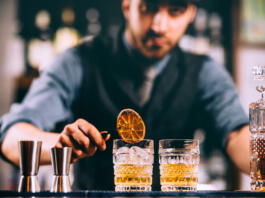 Portrait of barman adding ingredients and creating cocktail drinks on bar counter