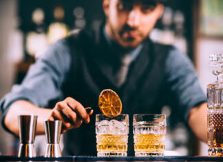 Recepti za rum koktajle, ki so hitro postali hiti letošnjega poletja Portrait of barman adding ingredients and creating cocktail drinks on bar counter