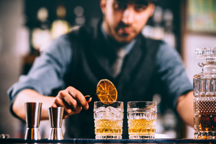 Portrait of barman adding ingredients and creating cocktail drinks on bar counter