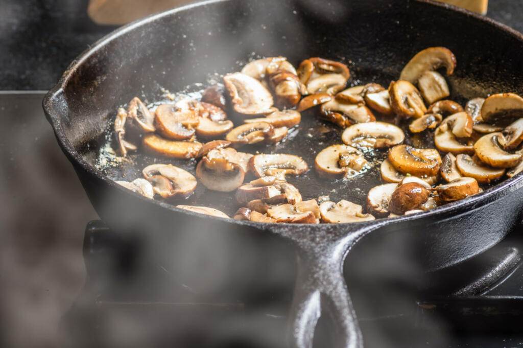 Sauteing sliced mushrooms in a cast iron skillet