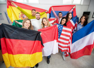 Študij v tujini? Tu boš dobil informacije iz prve roke Students holding various flags of different countries in the classroom, student exchange