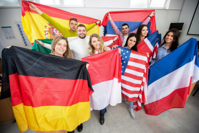 Students holding various flags of different countries in the classroom, student exchange