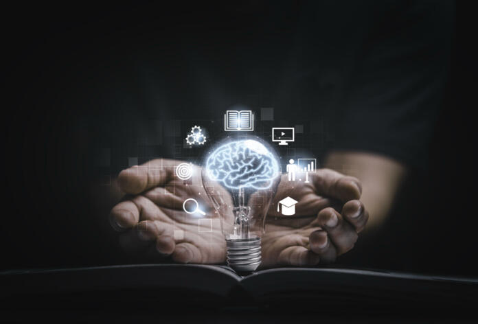 Virtual brain inside lightbulb on open book between two hand for creative thinking idea to solve problem from learning knowledge and innovation concept.