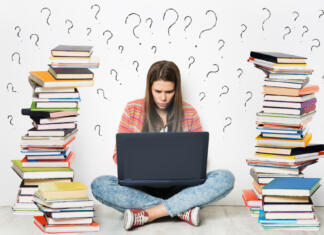 Ne pozabite na informativne dneve v Ljubljani in Mariboru Woman using Laptop. Student Girl working on Computer Search in Internet around Stacks of Books. Question Marks Drawn On White Wall Background. E Learning, Online Studying, Reading Books in Digital Library. Young Girl sitting on Floor next to heap of Books
