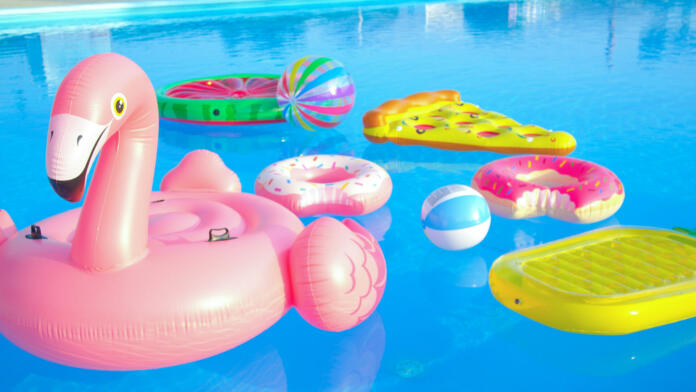 CLOSE UP: Trendy inflatable toys float around the empty pool on a sunny day as all social gatherings are cancelled until further notice due to coronavirus outbreak. Empty pool after a cancelled party.
