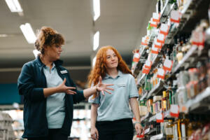 Grocery store manager training new female worker. Grocery store manager explaining work to a new saleswoman.