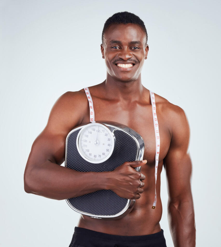 Rear view of one African American fitness model posing topless in a towel and looking muscular. Black male athlete rubbing his head while isolated on grey copyspace in a studio