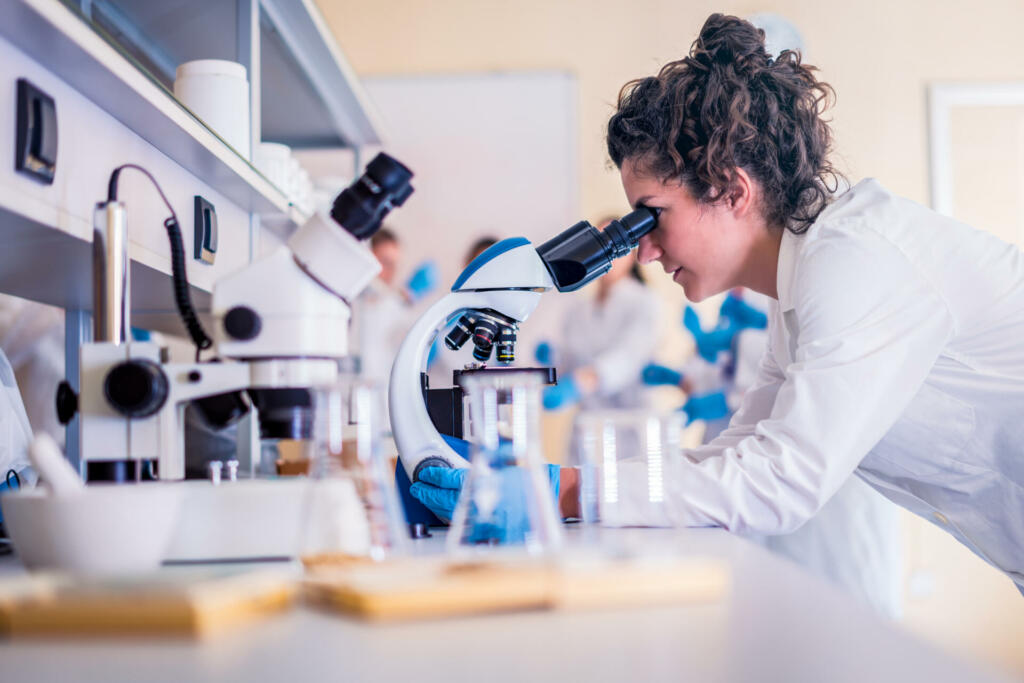 Scientist in lab doing research and using lab machines, test tubes, microscope and every laboratory equipment