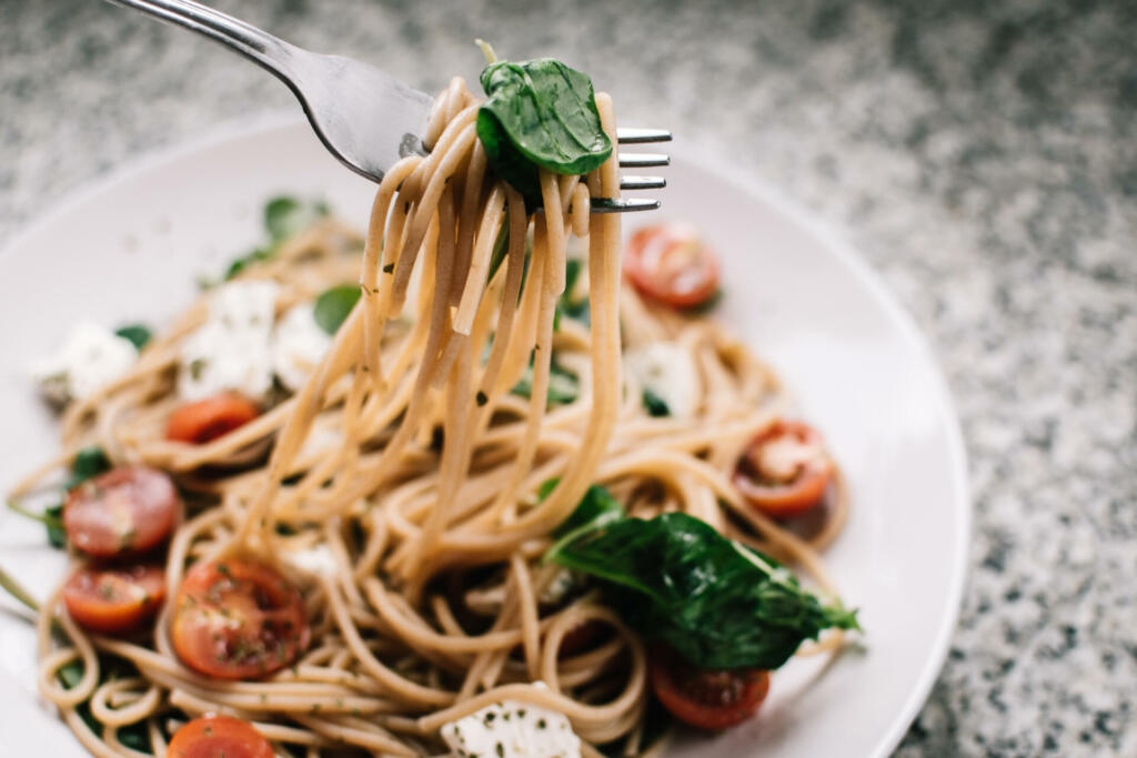 Selective focus photography of pasta with tomato and basil