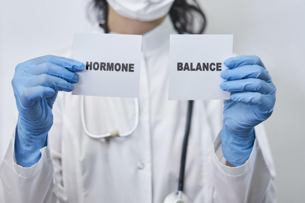 A female doctor holding two white cards with Hormone balance words. Hormone balance concept