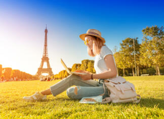 Zveza EUTOPIA študente vabi na Klub idej EUTOPA: Vse o dogodku in prijavi An Asian girl works on a laptop sitting on the grass on the Champ de Mars in Paris overlooking the Eiffel tower at sunset. Concept of remote work and freelancing