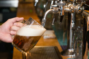 Close-up of bartender hand at beer tap pouring a draught lager beer