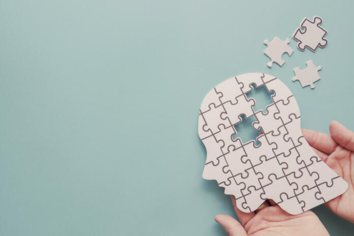 Hands holding brain with puzzle paper cutout, autism, Epilepsy and alzheimer awareness, seizure disorder, world mental health day concept