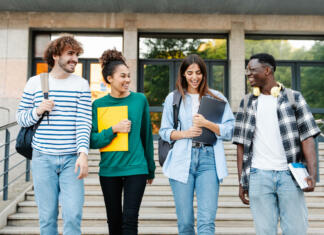 5 dvomov ob vstopu v prvi letnik študija Happy students walking together on university campus, chatting and laughing outdoors after classes
