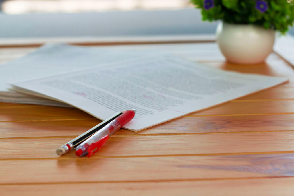red pen on blurred paperwork on wooden table in office