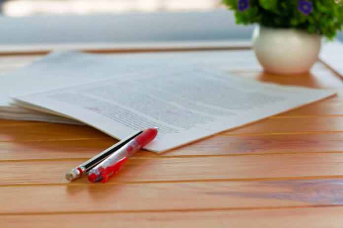 red-pen-on-blurred-paperwork-on-wooden-table-in-office-stockpack-istock red pen on blurred paperwork on wooden table in office