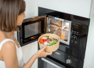 Plastike NIKOLI ne segrevaj v mikrovalovni pečici – tudi “microwave safe” je lahko nevarna Woman heating food with microwave machine at home, female using modern kitchen appliances