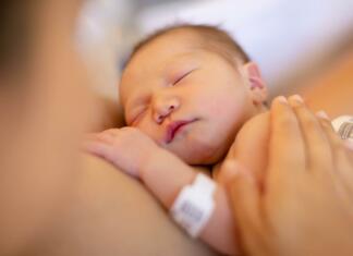 Sit dojenček bo zadovoljen dojenček A mother holding her newborn baby on her warm chest for skin on skin time at the hospital.