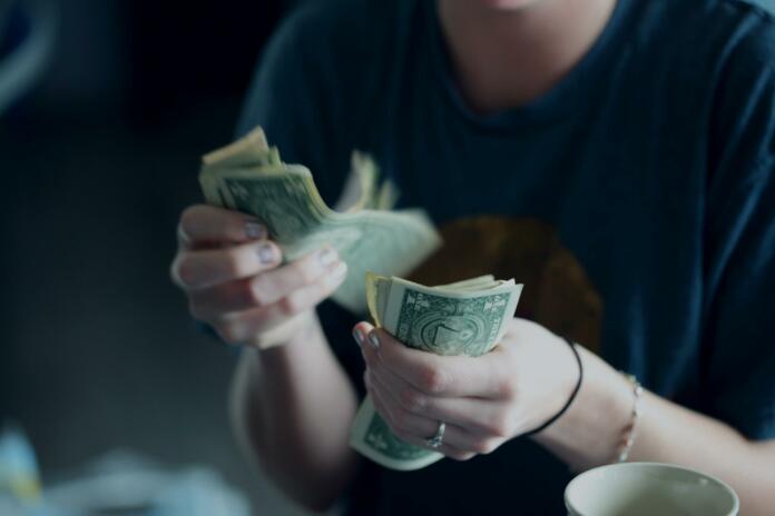 A twenty-four year old woman counting dollar bills.