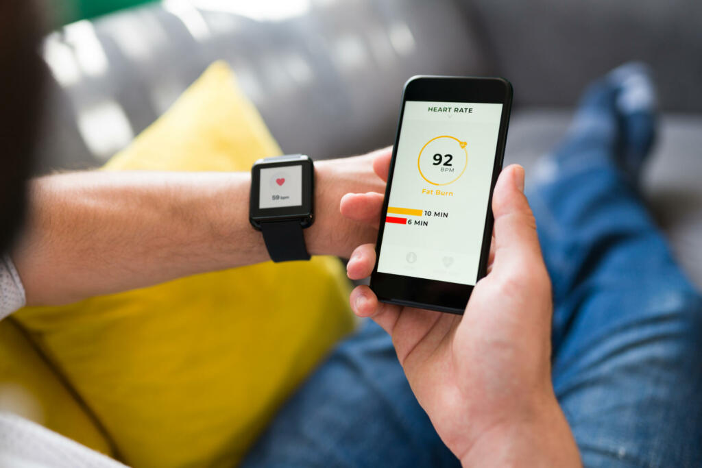 Adult person connecting a fitness app with his smartphone. Adult man checking his heart rate