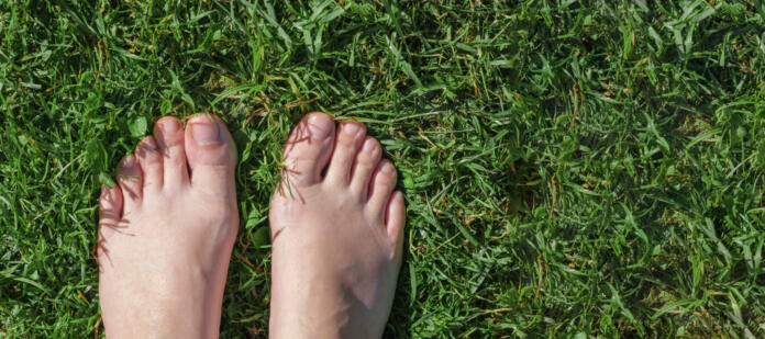 Bare feet on green grass. Selfie. Female feet on the green grass. Rustic lifestyle. View from above. Woman standing on a grass field. Top view. Freedom, summer relax concept. Earth Day.